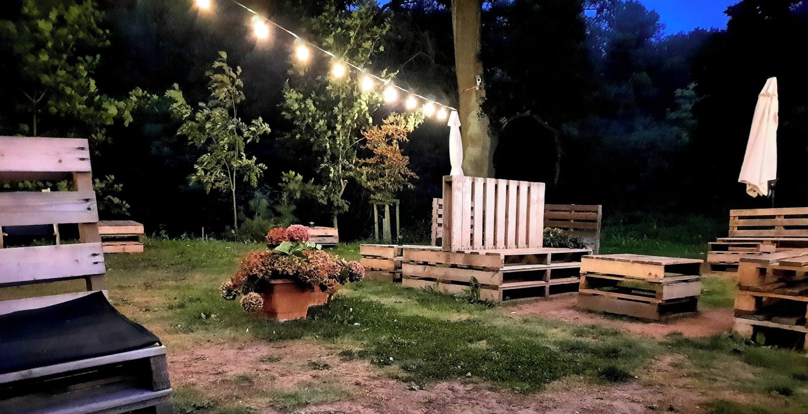 Posezení z palet pod řetězem světel za soumraku